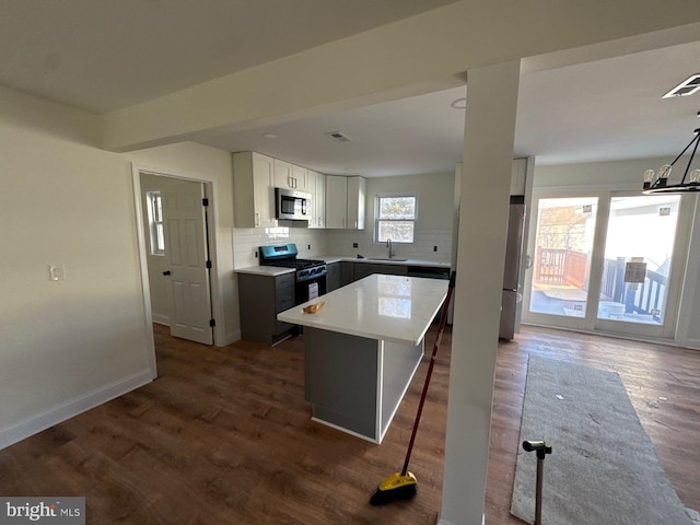 kitchen featuring stainless steel appliances, a kitchen island, decorative backsplash, and dark wood-style floors