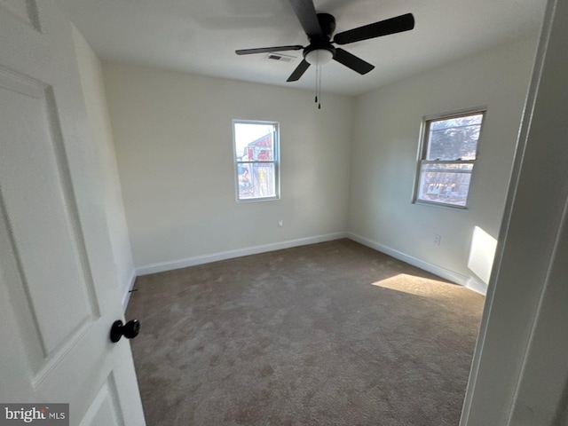 empty room with ceiling fan, carpet floors, visible vents, and baseboards