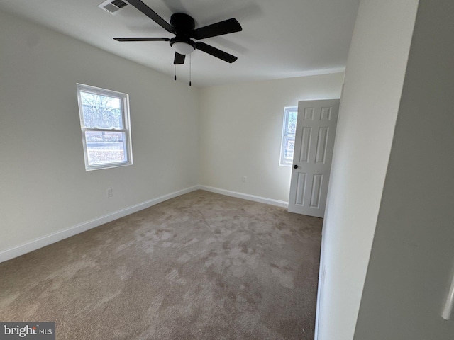 carpeted empty room featuring ceiling fan, visible vents, and baseboards