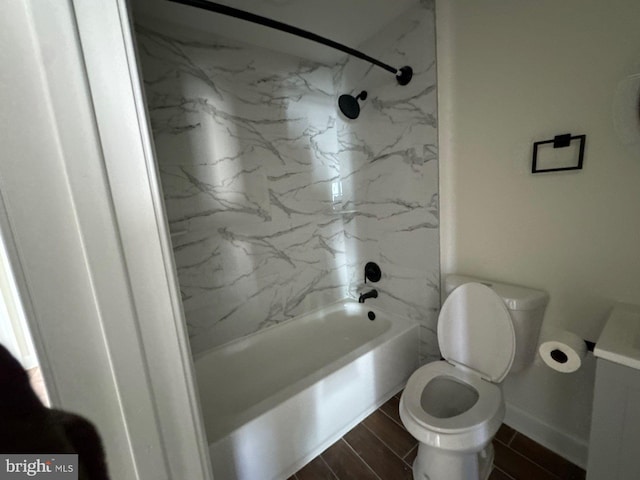 bathroom featuring wood tiled floor, baseboards, shower / bath combination, and toilet