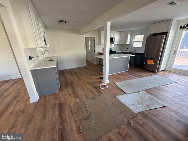 kitchen featuring dark wood finished floors, stainless steel appliances, tasteful backsplash, light countertops, and a sink