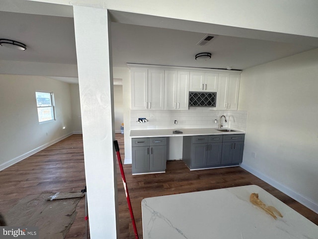 kitchen featuring tasteful backsplash, visible vents, a sink, and dark wood-type flooring