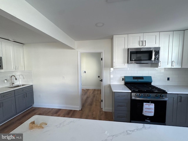 kitchen with dark wood-style floors, appliances with stainless steel finishes, a sink, and white cabinets