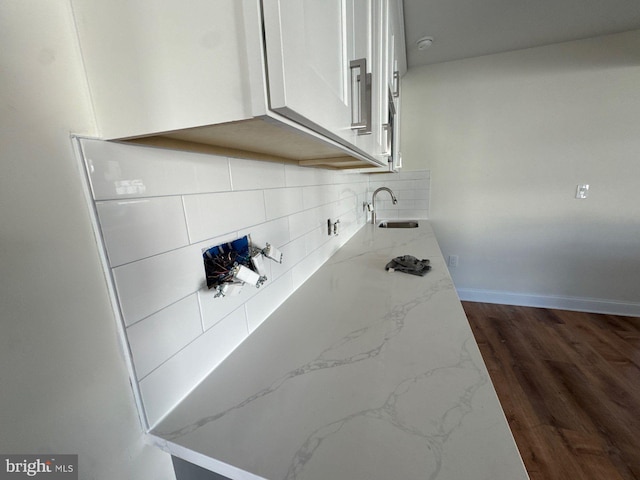 room details featuring baseboards, decorative backsplash, a sink, and wood finished floors