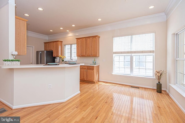 kitchen with light wood-style floors, freestanding refrigerator, light countertops, and crown molding