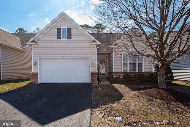 traditional-style house with a garage, driveway, and brick siding