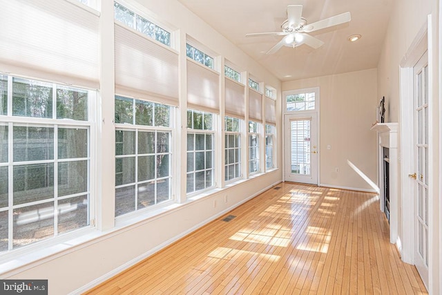 unfurnished sunroom featuring a ceiling fan, visible vents, and a fireplace