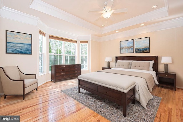 bedroom with ceiling fan, baseboards, light wood-type flooring, a raised ceiling, and crown molding