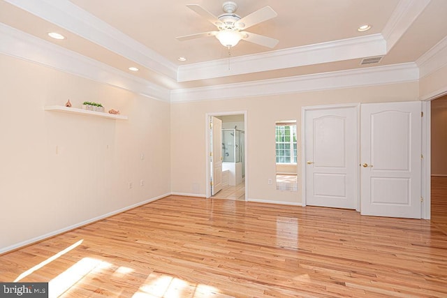 interior space featuring light wood finished floors, visible vents, a tray ceiling, and crown molding