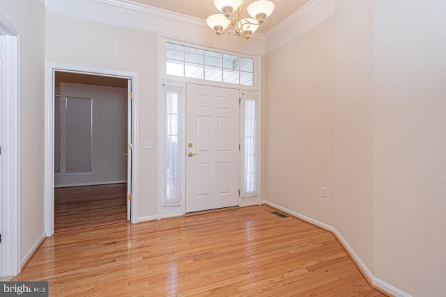 entrance foyer with visible vents, ornamental molding, light wood-style floors, a chandelier, and baseboards