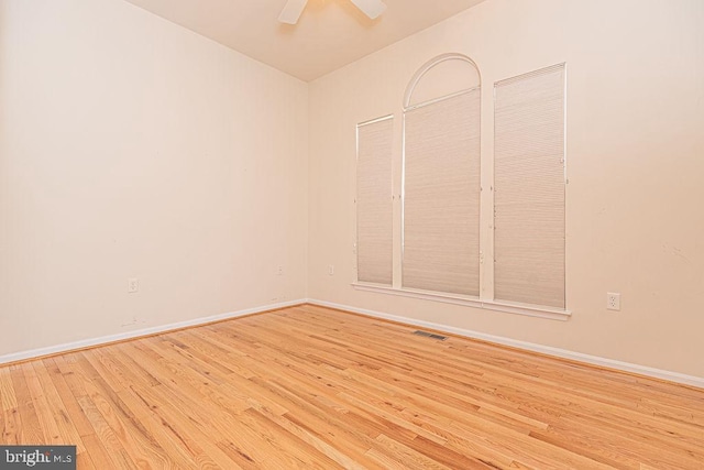 empty room with light wood-style floors, visible vents, baseboards, and a ceiling fan