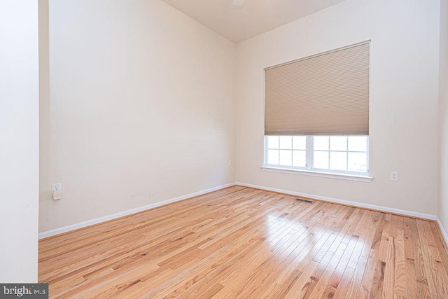 unfurnished room with wood-type flooring, visible vents, and baseboards