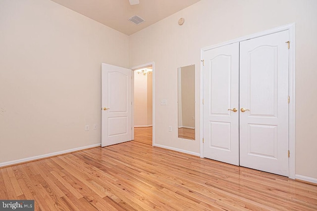 unfurnished bedroom with light wood finished floors, baseboards, visible vents, and a closet