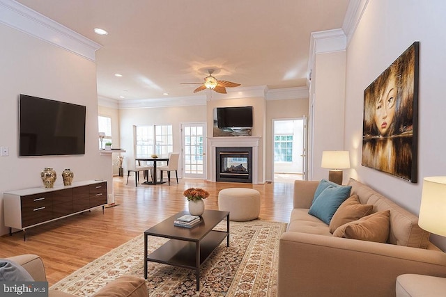 living area with ceiling fan, crown molding, light wood-type flooring, a multi sided fireplace, and recessed lighting