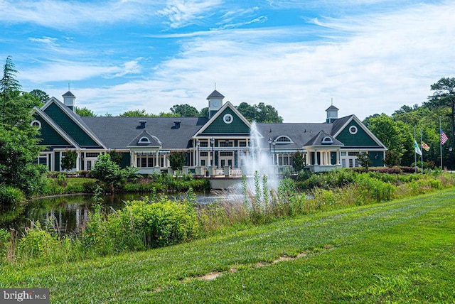 back of house featuring a water view and a lawn