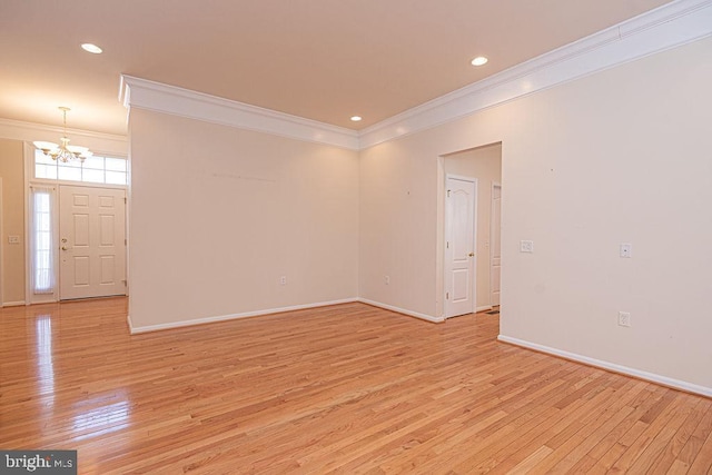 empty room featuring baseboards, light wood-style flooring, a chandelier, and crown molding