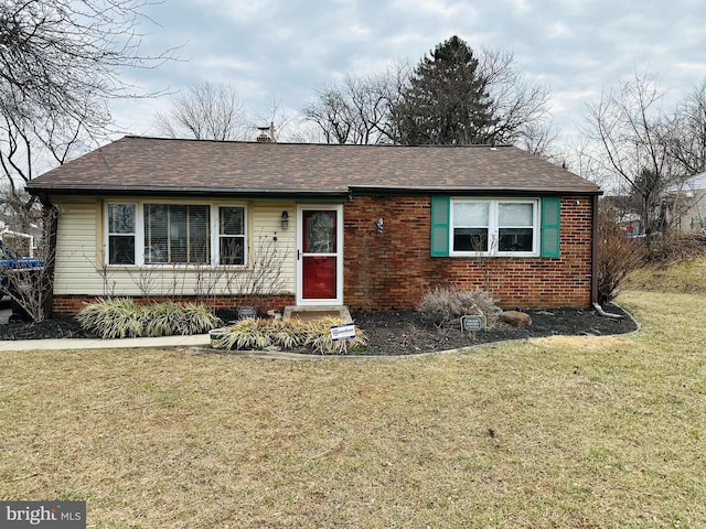 view of front of property featuring a shingled roof, a front lawn, and brick siding