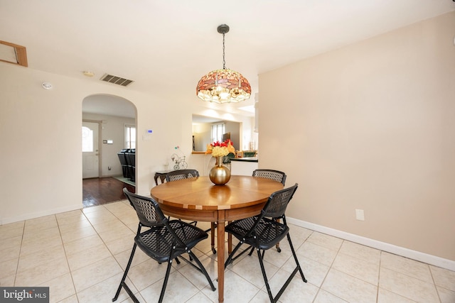 dining area featuring arched walkways, visible vents, baseboards, and light tile patterned floors