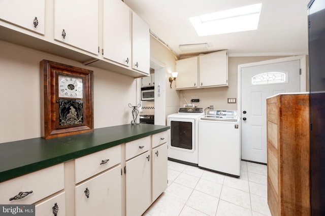 kitchen with a skylight, white cabinetry, washer and clothes dryer, and light tile patterned floors