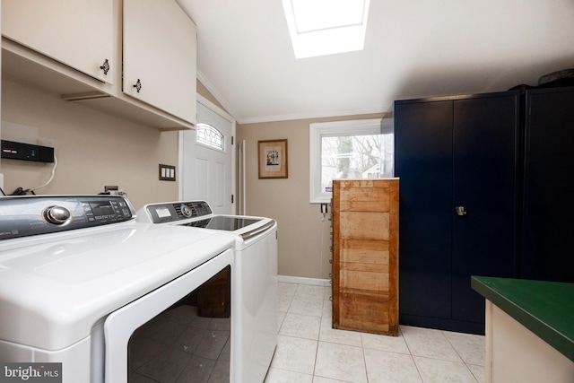 laundry room with light tile patterned floors, a skylight, baseboards, cabinet space, and washing machine and clothes dryer