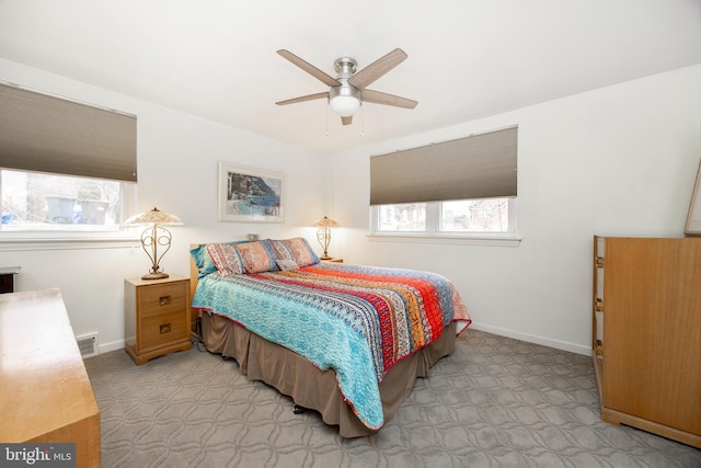 bedroom with light carpet, ceiling fan, visible vents, and baseboards