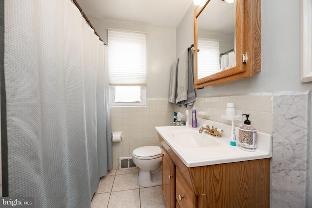 full bath featuring tile walls, visible vents, toilet, vanity, and tile patterned flooring