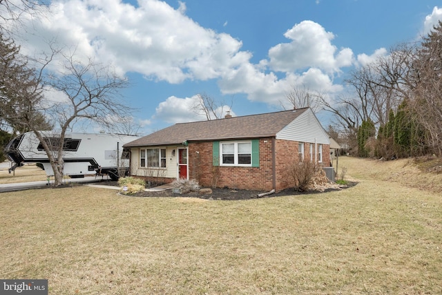 single story home with brick siding, a front lawn, and cooling unit