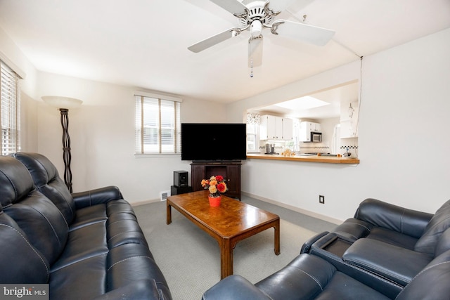 living room featuring carpet floors, baseboards, and a ceiling fan