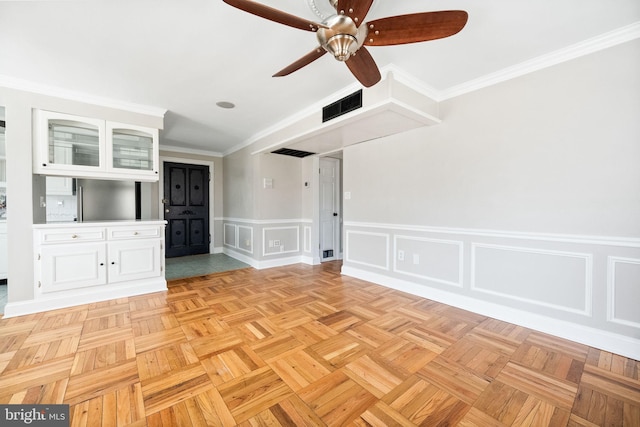 interior space with a decorative wall, visible vents, crown molding, and ceiling fan