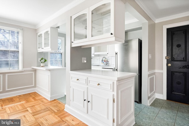 kitchen with white cabinetry, plenty of natural light, freestanding refrigerator, and a sink