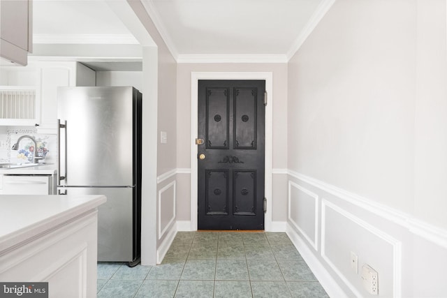 interior space with crown molding, dishwasher, light countertops, freestanding refrigerator, and a sink