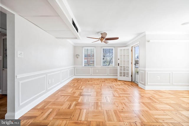 empty room with a decorative wall, crown molding, and a ceiling fan