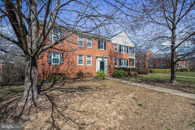 colonial house featuring a front lawn and brick siding