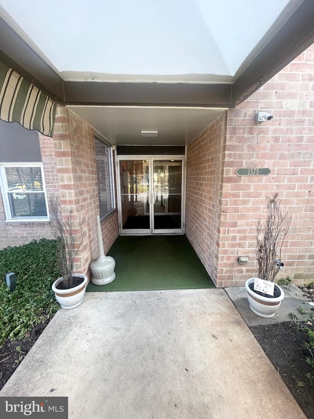 property entrance with brick siding and a patio area