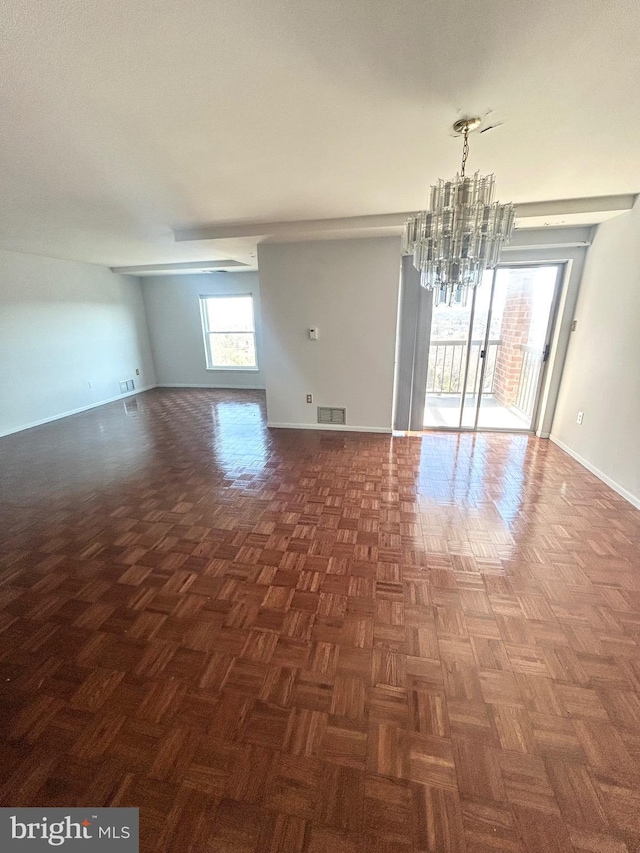 unfurnished room featuring a chandelier, visible vents, and baseboards