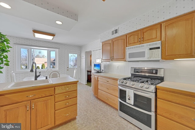 kitchen featuring white microwave, visible vents, wallpapered walls, and range with two ovens