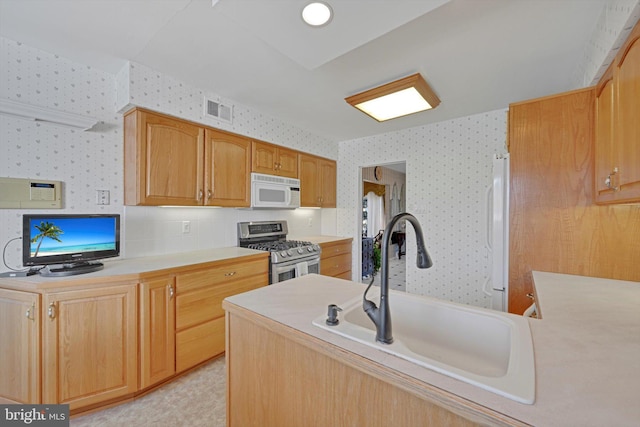 kitchen with visible vents, wallpapered walls, light countertops, white appliances, and a sink