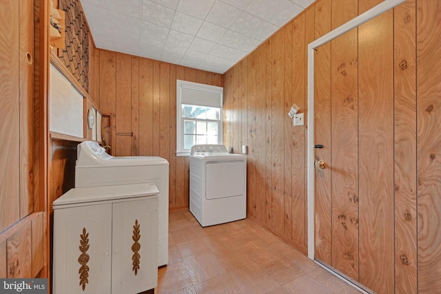 laundry room with cabinet space, separate washer and dryer, and wooden walls