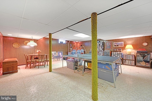 game room featuring tile patterned floors, a drop ceiling, and wooden walls