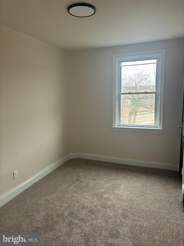 carpeted spare room featuring baseboards