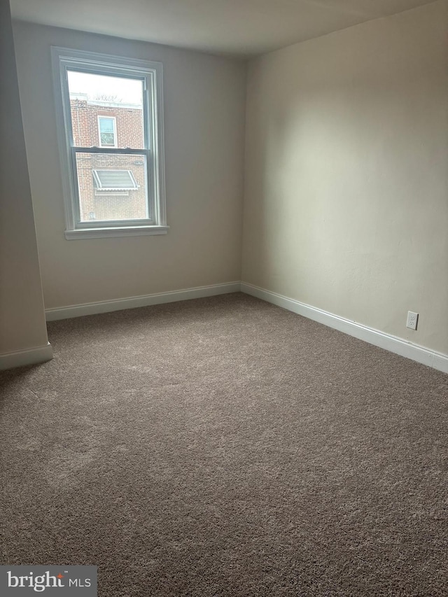 carpeted spare room featuring baseboards