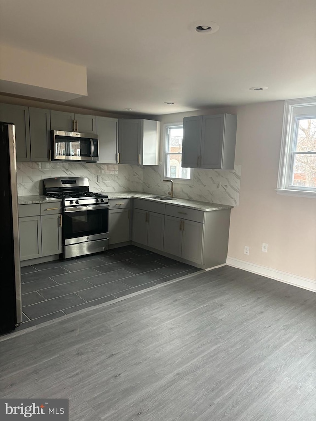 kitchen featuring appliances with stainless steel finishes, backsplash, and gray cabinetry