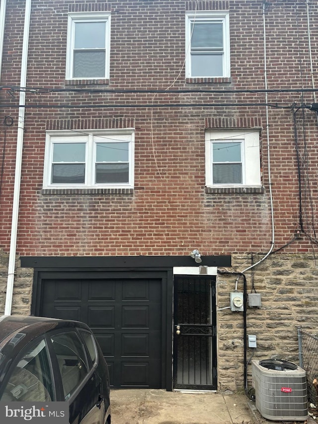 townhome / multi-family property featuring brick siding, an attached garage, and central air condition unit