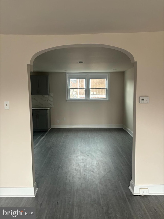 empty room with baseboards and dark wood-type flooring