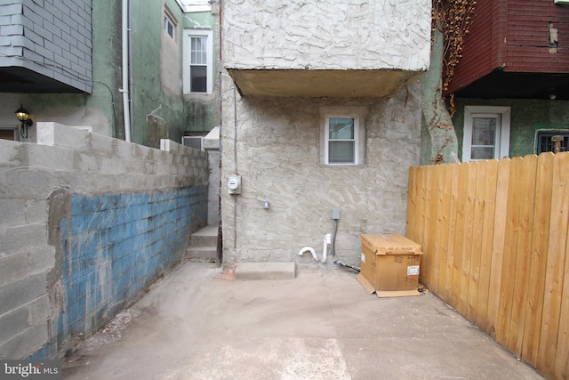 view of home's exterior with stone siding, stucco siding, a patio, and fence