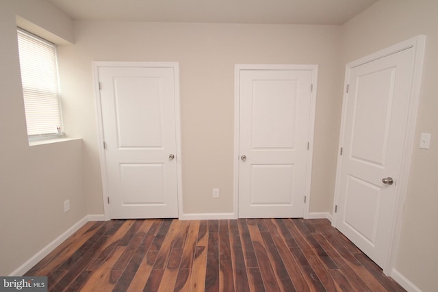 unfurnished bedroom with baseboards and dark wood-style flooring