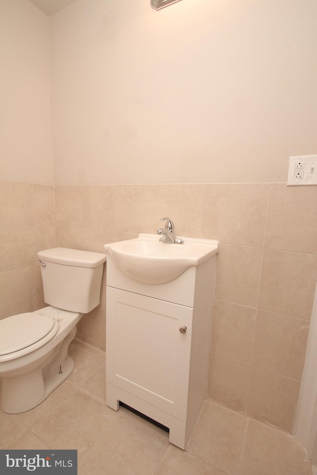 half bath featuring toilet, wainscoting, vanity, and tile patterned flooring