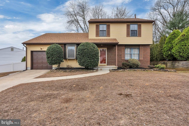 traditional-style home with a garage, fence, concrete driveway, and brick siding