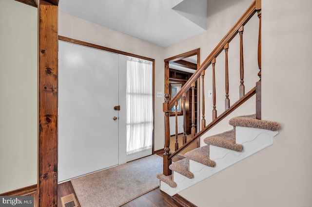 foyer entrance with visible vents, stairway, and wood finished floors