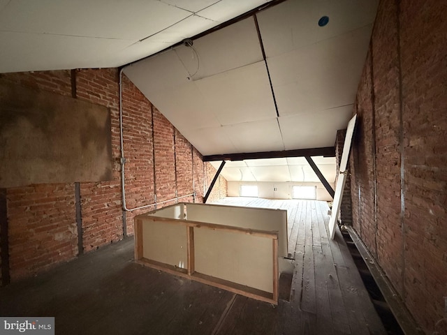 basement featuring brick wall and wood-type flooring